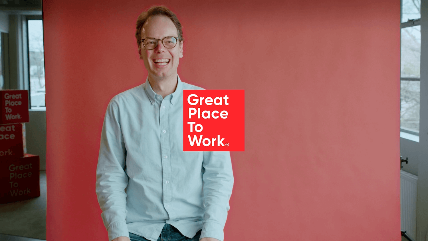 Lachende collega van Great Place To Work voor rood doek op filmset