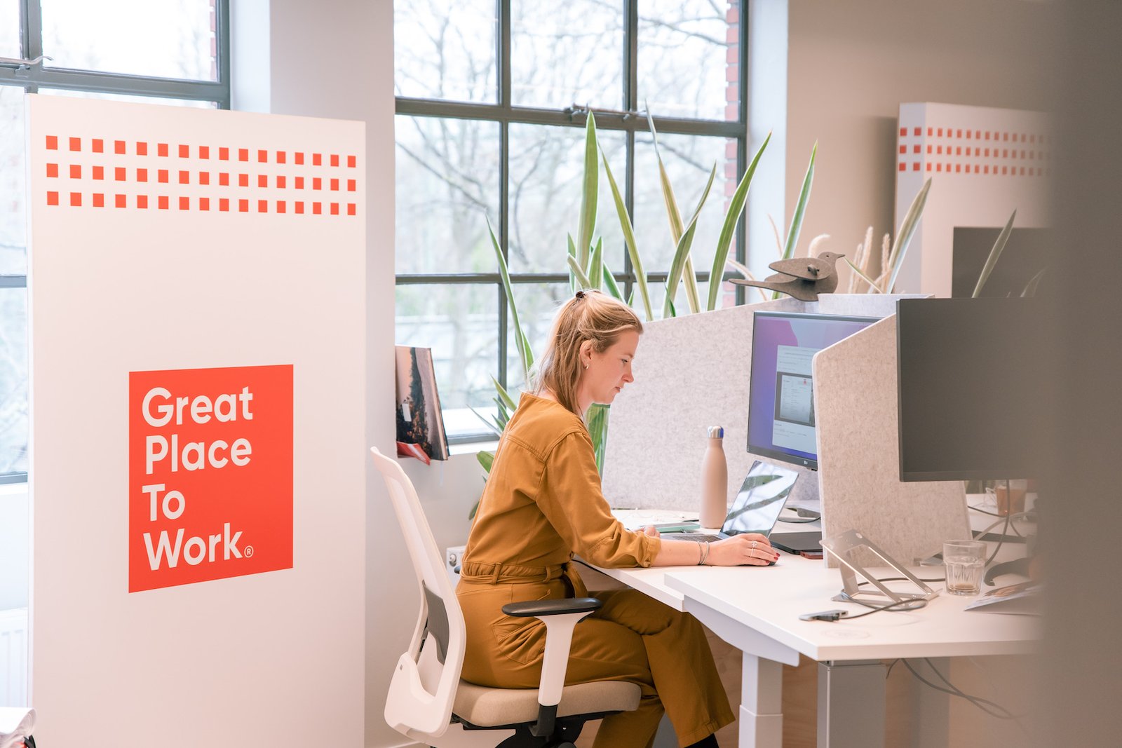 Vrouw werkt achter laptop op het kantoor van Great Place To Work