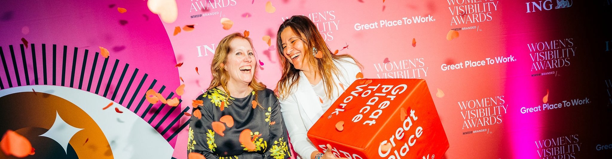 Twee lachende vrouwelijke collega's van Dopper poseren met Great Place To Work kubus tijdens uitreiking Best Workplaces for Women 2024