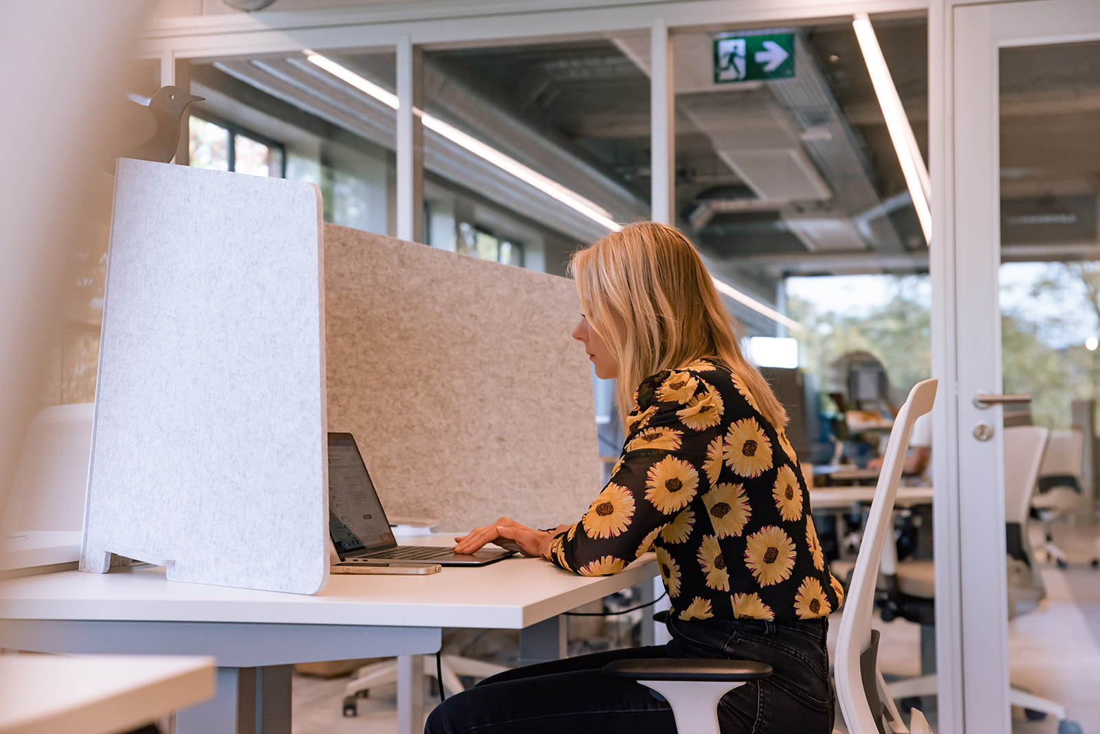Medewerker van Great Place To Work met gebloemde top werkt achter laptop